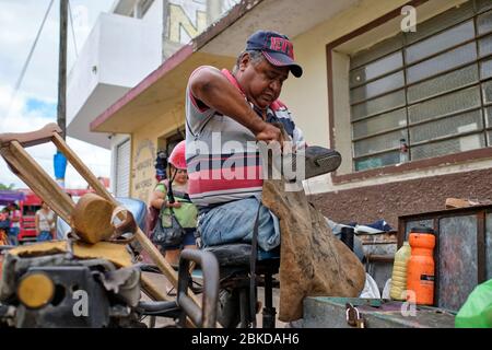 Cordonnier traditionnel réparant les vieilles chaussures dans les rues du marché de Tizmin. Banque D'Images