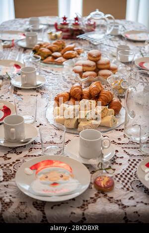 Table de Noël avec tortillas, croissant, tarte au fromage et serviettes de table du père noël sur des assiettes Banque D'Images