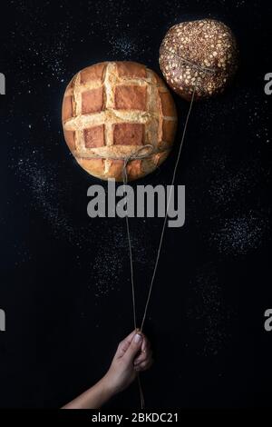 Deux pains croustillants frais comme des ballons sur un ciel de Nigh et des étoiles de farine dans un fond noir Banque D'Images