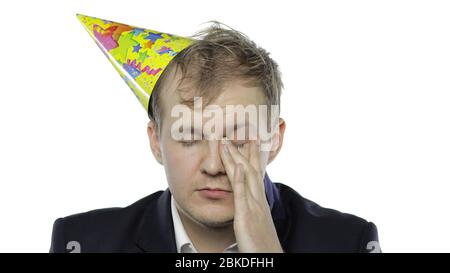 Portrait de l'homme jeune et endormi de la planche avec un hanguleur. Émotions. Homme d'affaires en costume et casquette festive avec bouée. Fond blanc. Concept de fête d'anniversaire de bureau Banque D'Images