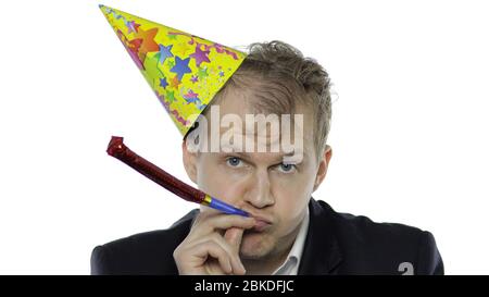 Portrait du jeune homme endormi avec hangueule sifflement. Émotions. Un homme d'affaires en costume et un bonnet festif à la porte de l'appareil photo. Fond blanc. Concept de fête d'anniversaire de bureau Banque D'Images