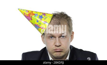 Portrait de l'homme jeune et endormi de la planche avec un hangover regardant l'appareil photo. Émotions. Homme d'affaires en costume et casquette festive avec bouée. Fond blanc. Concept de fête d'anniversaire de bureau Banque D'Images