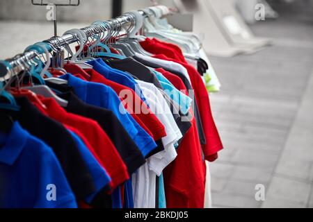 T-shirts de polo colorés pour l'homme sur des cintres dans un magasin. Vente de vêtements pour hommes Banque D'Images