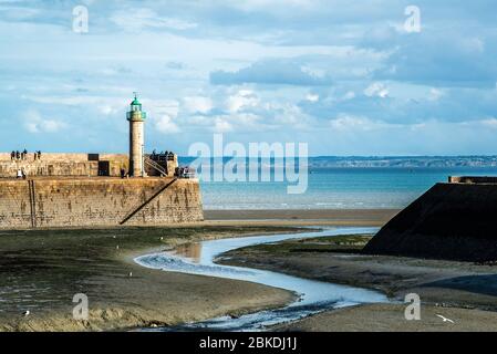 Vue panoramique à marée basse d'un port en Bretagne, France, avec un phare de toit vert et de nombreuses personnes sur le quai Banque D'Images