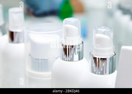 Rangée de bouteilles blanches vierges avec produits cosmétiques. Crèmes hydratantes et autres moyens pour les soins de la peau du visage et du corps Banque D'Images