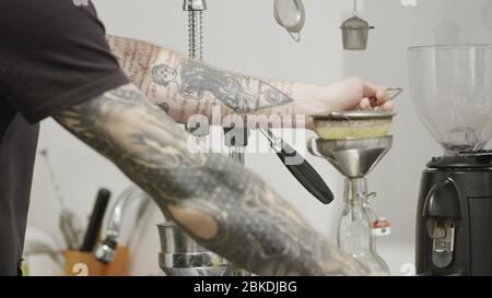 Le barista avec un tatouage prépare du jus naturel au citron dans une bouteille pour prendre un verre d'été. Ralenti, vidéo Full HD, 240 ips, 1080 p. Banque D'Images