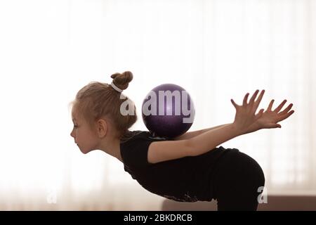 Belle petite fille faisant des exercices avec une balle de fitness. Concept de sport et de mode de vie sain. Banque D'Images