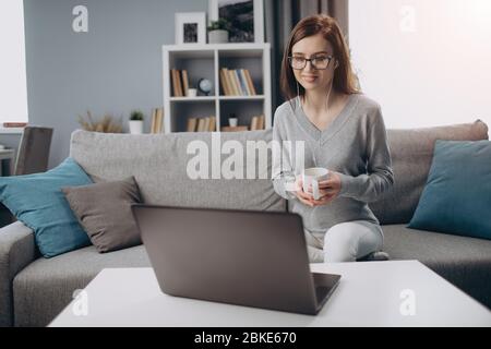Femme dans un écouteur ayant une conférence en ligne sur ordinateur portable Banque D'Images