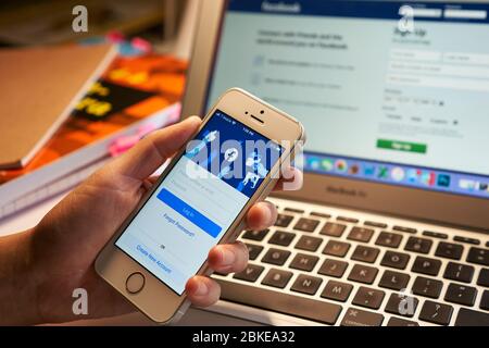Une femme utilise l'application mobile Facebook sur son smartphone. Banque D'Images