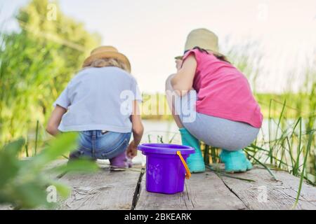 Enfants deux filles jouant ensemble avec l'eau sur le lac sur la jetée en bois dans les roseaux Banque D'Images