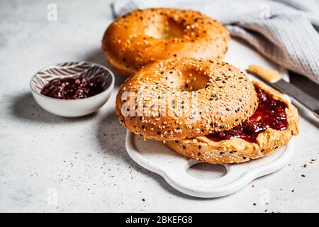 Bagels au beurre d'arachide et confiture de baies sur un tableau blanc. Concept alimentaire végétalien. Banque D'Images