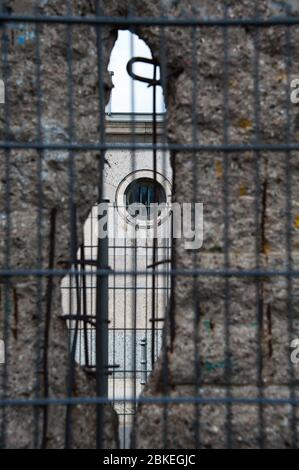 Vue rapprochée d'un trou dans le mur de Berlin. Voir ce qui reste du mur montrant des armatures métalliques, et la section endommagée à travers une clôture Banque D'Images