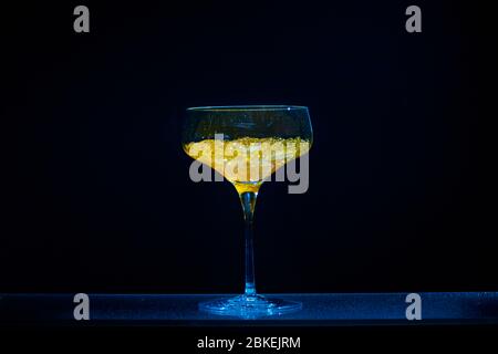 Un verre martini unique, un écran lumineux, un caviar d'eau de couleur jaune dans le style d'un cocktail. Verre de couleur bleu vif et bleu fluo Banque D'Images