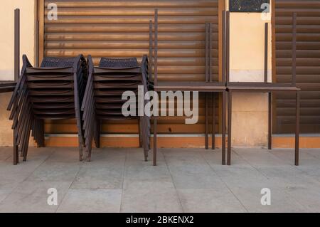 Chaises en plastique marron empilées à côté des tables extérieures. Restaurant fermé par le coronavirus Banque D'Images