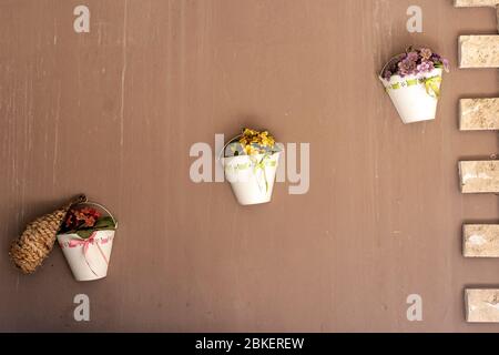 décoration murale en pot de fleurs accrochée sur un mur avec une plante artificielle rose, jaune et rouge Banque D'Images