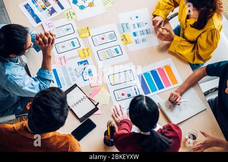 vue du haut le développeur et concepteur d'interface utilisateur d'ux asiatique remue-méninges sur la conception d'éléments filaires d'interface d'application mobile sur table avec le dossier client et le code couleur à m. Banque D'Images