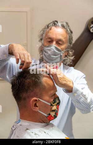 Salon de coiffure à Essen-Rüttenscheid, premier client après 6 semaines, magasin fermé en raison de la crise de Corona, maître de coiffure et client avec bouche n Banque D'Images