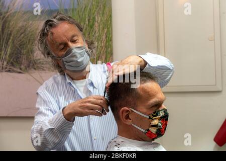 Salon de coiffure à Essen-Rüttenscheid, premier client après 6 semaines, magasin fermé en raison de la crise de Corona, maître de coiffure et client avec bouche n Banque D'Images