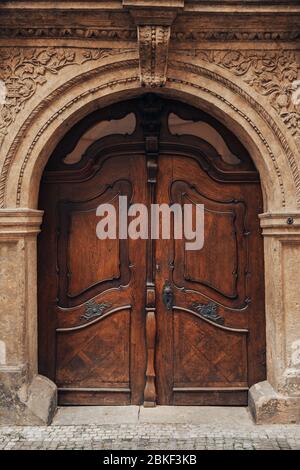 Ancienne porte en bois en chêne foncé massif avec éléments décoratifs, ouverture en forme de trou de serrure forgé, pilaster et stuc sur l'arche Banque D'Images