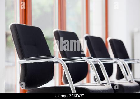 Chaises dans une rangée dans une salle d'attente ou un salon ensoleillé - se concentrer sur l'accoudoir de la première chaise Banque D'Images