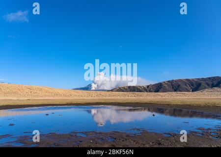 La prairie de Kusasenri en janvier, à la fumée du mont Naka (également appelé Nakadake ou Naka-Dake) réflexions à travers l'étang d'eau. Parc national de l'ASO Kuju, Kumamoto Banque D'Images