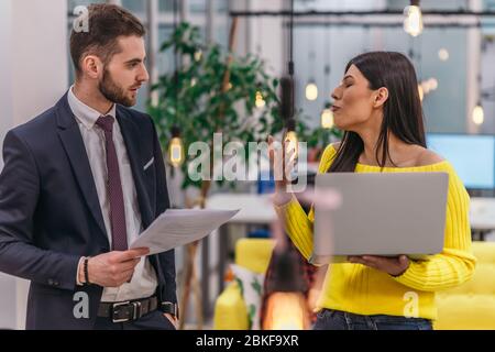 Le responsable explique à son employé comment terminer ses tâches. Collègues discutant d'un projet en se tenant dans un bureau. Banque D'Images