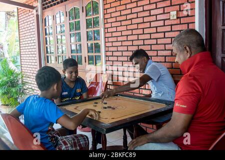 Les familles qui essaient de garder la vie aussi normale que possible. Jouer à des jeux de société à la maison parce que le couvre-feu et le verrouillage sont imposés dans le pays. Colombo, Sri Lanka. Banque D'Images