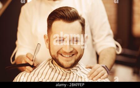 Barber man rase sa barbe et coupe les cheveux au client dans le barbershop. Banque D'Images