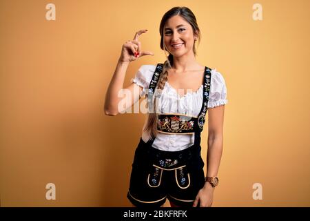 Jeune femme allemande brunette célébrant l'Octoberfest portant une robe traditionnelle souriant et confiant gestuelle avec la main faisant petite SIG Banque D'Images