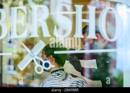 Mayence, Allemagne. 04 mai 2020. Un coiffeur coupe les cheveux d'un client dans le 'Barbershop' dans le centre-ville. La boutique du salon de coiffure est complètement réservée, les clients font la queue devant la boutique. Les terrains de jeux pour enfants et les équipements d'entraînement en plein air sont de nouveau ouverts, les coiffeurs sont autorisés à couper les cheveux à nouveau. Des règles d'hygiène strictes sont toutefois toujours applicables. Crédit: Andreas Arnold/dpa/Alay Live News Banque D'Images