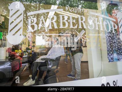 Mayence, Allemagne. 04 mai 2020. Un coiffeur coupe les cheveux d'un client dans le 'Barbershop' dans le centre-ville. La boutique du salon de coiffure est complètement réservée, les clients font la queue devant la boutique. Les terrains de jeux pour enfants et les équipements d'entraînement en plein air sont de nouveau ouverts, les coiffeurs sont autorisés à couper les cheveux à nouveau. Des règles d'hygiène strictes sont toutefois toujours applicables. Crédit: Andreas Arnold/dpa/Alay Live News Banque D'Images