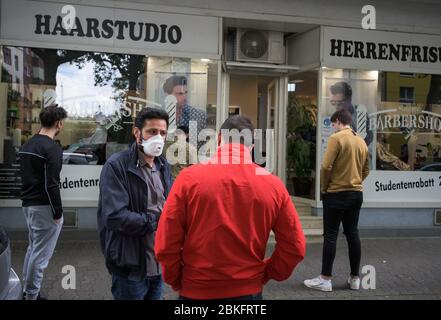 Mayence, Allemagne. 04 mai 2020. Les gens sont d'accord avec la photo de derrière Dogan (2ème de gauche), directeur de succursale de la 'Barbershop', parle à un client debout dans une file d'attente devant la boutique. Le barbershop est complètement réservé, les clients font la queue devant la boutique. Les terrains de jeux pour enfants et les équipements d'entraînement en plein air sont de nouveau ouverts, les coiffeurs sont autorisés à couper les cheveux à nouveau. Des règles d'hygiène strictes sont toutefois toujours applicables. Crédit: Andreas Arnold/dpa/Alay Live News Banque D'Images