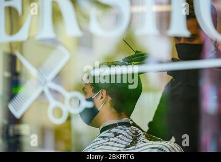 Mayence, Allemagne. 04 mai 2020. Un coiffeur coupe les cheveux d'un client dans le 'Barbershop' dans le centre-ville. La boutique du salon de coiffure est complètement réservée, les clients font la queue devant la boutique. Les terrains de jeux pour enfants et les équipements d'entraînement en plein air sont de nouveau ouverts, les coiffeurs sont autorisés à couper les cheveux à nouveau. Des règles d'hygiène strictes sont toutefois toujours applicables. Crédit: Andreas Arnold/dpa/Alay Live News Banque D'Images