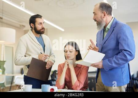Deux hommes barbus et une jeune femme qui ont des disputes lors d'une réunion d'affaires, photo horizontale Banque D'Images