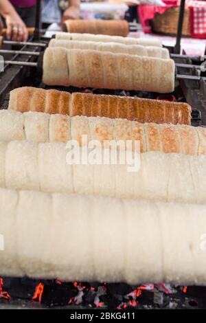 Kurtos kalacs ou des gâteaux de cheminée, la préparation de la cuisine sur le charbon de bois, la rue de cuisine traditionnelle hongroise, pendant le festival de la nourriture. Kurtos Kalacs traditiona Banque D'Images