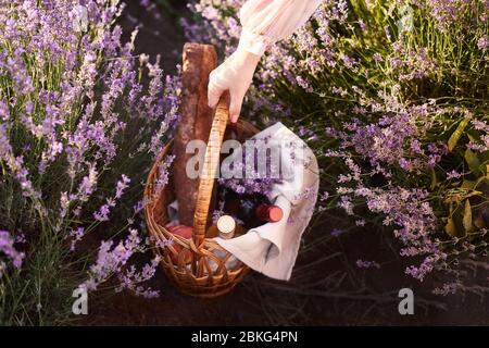 fille dans la robe romantique avec panier en osier avec vin et pain dans sa main recherche un bon endroit pour pique-nique Banque D'Images