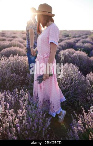 Couple amoureux. Jeune fille en robe romantique et homme dans les champs de lavande Banque D'Images