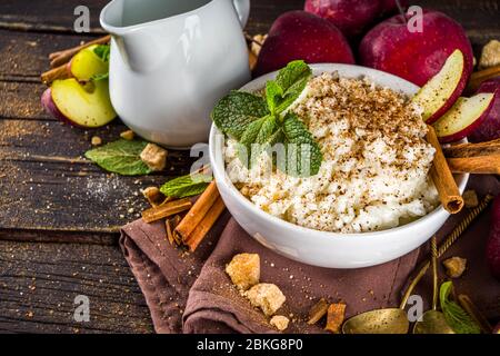 Petit déjeuner chaud d'automne ou boudin ou boudin de déjeuner avec pomme et épices. Porridge de riz à la cannelle et aux pommes rouges, sur un fond rustique en bois. Banque D'Images