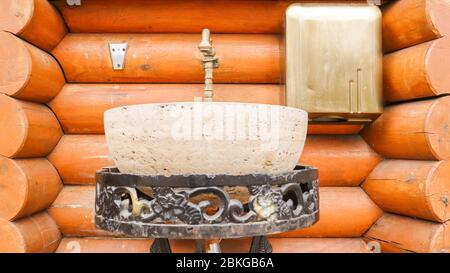 Un lavabo en pierre sur un support en métal forgé dans une maison en bois. Intérieur dans une maison en bois Banque D'Images