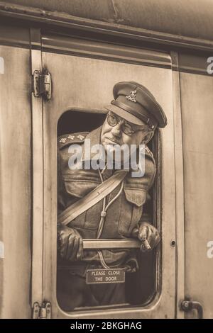 Sepia gros plan, homme des années 1940 comme capitaine de garde à domicile de la Seconde Guerre mondiale (Arthur Lowe lookown) regardant la fenêtre de train d'époque Severn Valley Railway. Banque D'Images