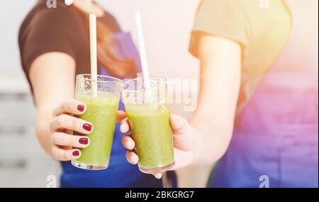 Les mains de jeunes filles tiennent dans des verres détox smoothies, couleur verte, gros plan. Banque D'Images