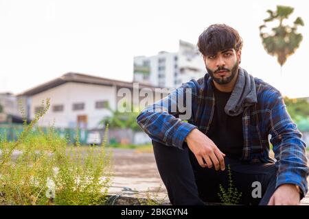 Jeune homme hipster indien barbu assis dans les rues urbaines Banque D'Images