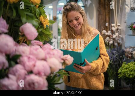 Jeune femme tenant le fichier dans la boutique de fleurs Banque D'Images