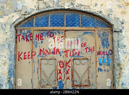 Détail d'un message peint sur la porte d'un bâtiment abîmé dans le village de Marsaxlokk, Malte. Banque D'Images
