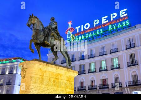 La célèbre enseigne publicitaire Tio Pepe plane sur une statue du roi Carlos III, dans la Puerta del Sol, Madrid, Espagne. Banque D'Images