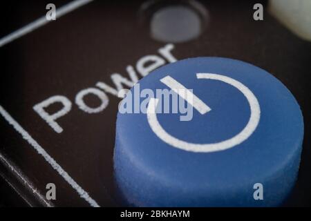 Macro extrême d'un bouton d'alimentation bleu sur une télécommande pour un téléviseur Banque D'Images