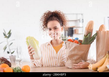 Jeune femme avec des produits frais du marché à la maison Banque D'Images