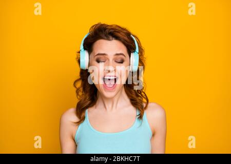 Photo de jolie dame drôle écouter technologie moderne écouteurs chansons bonne humeur chanter fort réjouissant porter décontracté teal tank-top isolé vif Banque D'Images