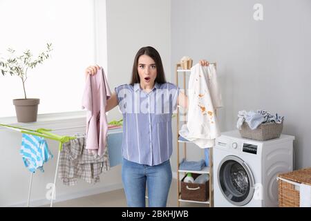 Jeune femme décontente de faire du linge à la maison Banque D'Images