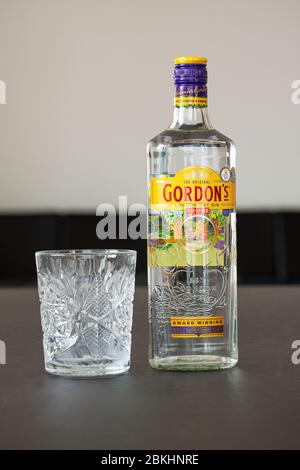 Une bouteille de Gin de Gordon et un verre de cristal sur une table. Gordon est une marque du gin sec londonien le plus vendu au monde, propriété des British Spirits c Banque D'Images